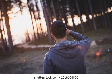 man with hat in forest looking at the sunset