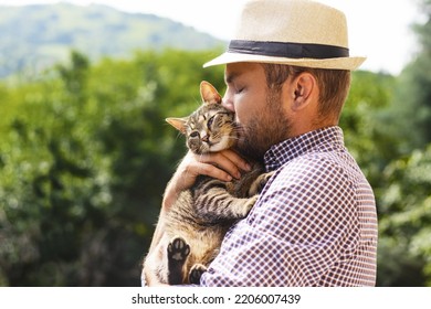 Man In Hat Gently Kissing His Cat.