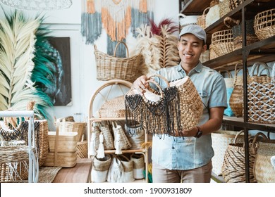 man in the hat holds and looks at the woven bag at the craft shop - Powered by Shutterstock