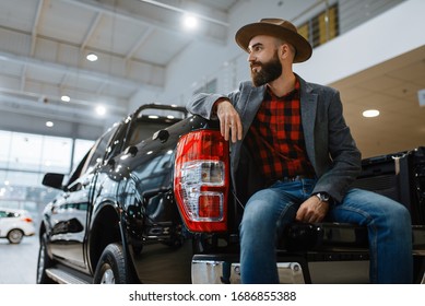 Man In Hat Poses At Pickup Truck In Car Dealership