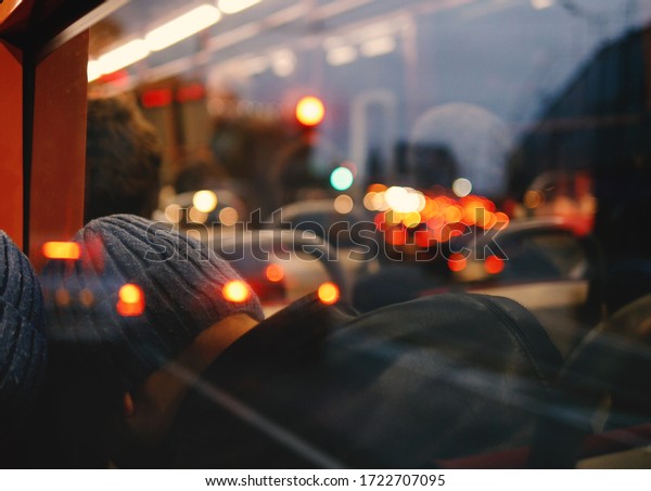 A man in a hat is sleeping on the bus, lights\
in the background