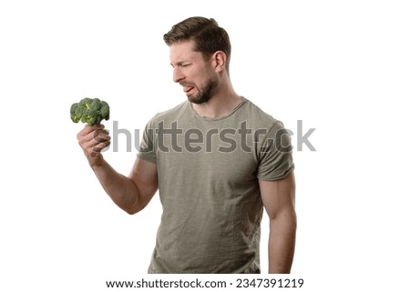 man hates disgusting broccoli while hold it in hands and show with his face he do not like the green healthy vegetable 