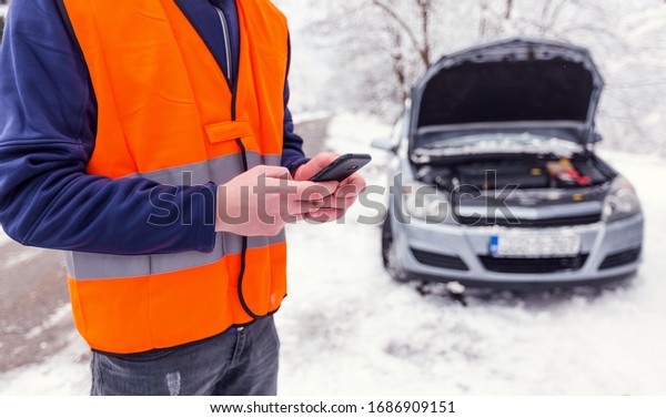 Man have trouble with his car and using phone\
to call car assistance