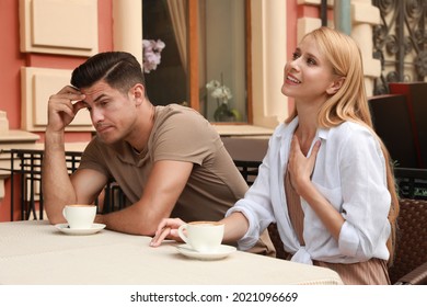 Man Having Boring Date With Talkative Woman In Outdoor Cafe