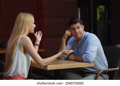 Man Having Boring Date With Talkative Woman In Cafe