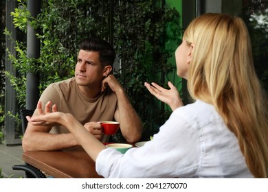 Man Having Boring Date With Talkative Woman In Outdoor Cafe