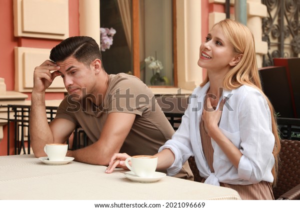 Man having boring date with talkative woman in\
outdoor cafe