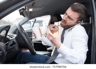 Man having breakfast and driving seated in his car