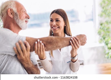 Man having chiropractic arm adjustment. Physiotherapy, sport injury rehabilitation. Senior man exercises in center for chiropractic.