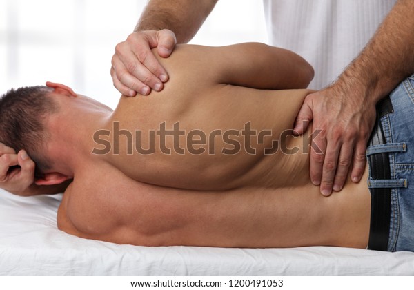 Man having chiropractic\
back adjustment. Osteopathy, acupressure, sport injury\
rehabilitation concept