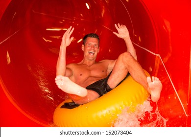 Man Having Fun Sliding Down A Waterslide In Public Swimming Pool