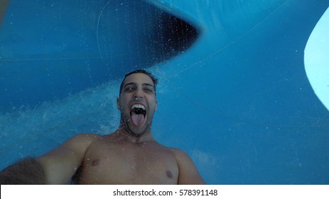 Man Having Fun And Sliding Down In A Water Slide