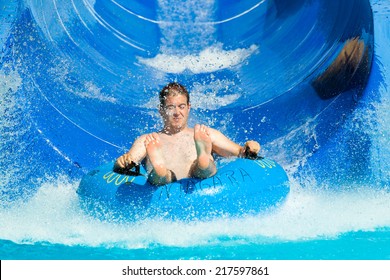 Man having fun, sliding at water park.