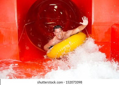 Man Having Fun In Water Slide At Public Swimming Pool