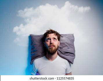 Man having problems/ insomnia, laying in bed on pillow, looking up to gray cloud over his head, copy space  