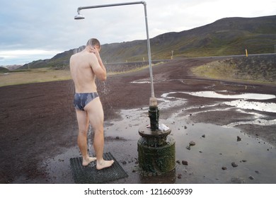 Man Having A Shower Outside. Top Destinations In North Iceland. Hot Wather From The Ground. Mountains Background.