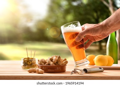 Man Having A Snack In The Countryside With A Glass Of Beer In Hand And A Table Full Of Snacks