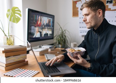 Man Having Take Away Food At The Table In Home Office While Having Video Conference Call Via Computer. Stay At Home And Work From Home. Eating Lunch By Laptop During Teleworking. Break Working