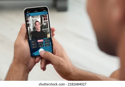 Man Having Workout With Personal Trainer Via Smartphone At Home, Closeup