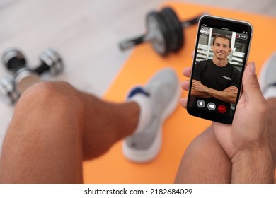 Man Having Workout With Personal Trainer Via Smartphone At Home, Closeup