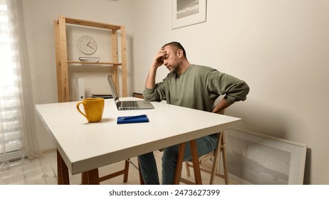 Man with headache while working on a laptop.