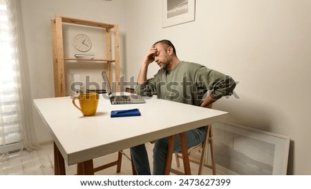 Man with headache while working on a laptop.
