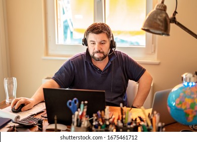 Man with headphones having conference call online at home office with laptops. Working from home during quarantine and self isolation period at pandemic. Manager upset with markets falling down