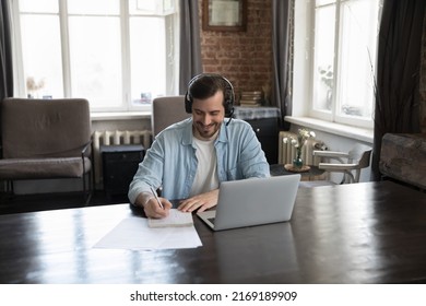 Man In Headset Writing On Copybook While Listen On-line Tutor During Distancing Class Via Video Call App On Laptop. Effective E-learning Using Internet, Virtual Meeting Event, Education, Tech Concept