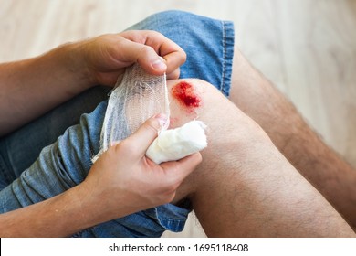 Man Heals The Wound On His Knee At Home. Holding The Bandage At The Hands