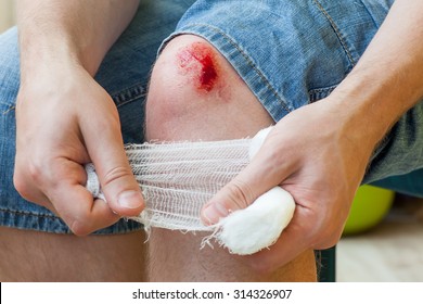 Man Heals The Wound On His Knee At Home. Holding The Bandage At The Hands 