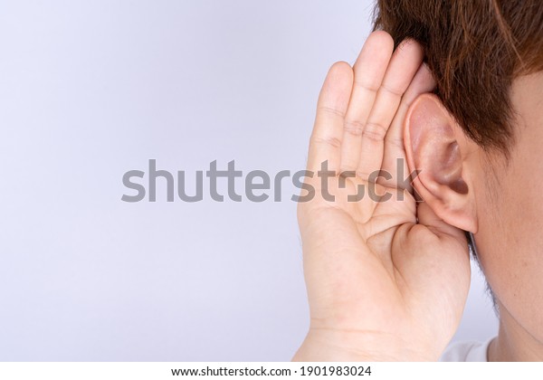 man hearing loss\
or hard of hearing and cupping his hand behind his ear isolate grey\
background, Deaf concept.