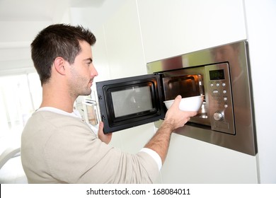 Man Heating Food In Microwave