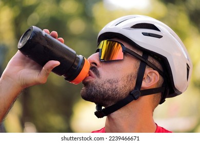man with helmet and cycling goggles drinking water - Shutterstock ID 2239466671