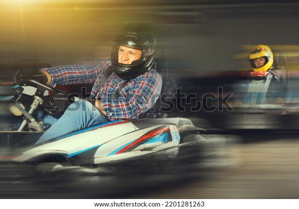Man in helmet driving racing
car for karting in a circuit lap in sport club, people on
background