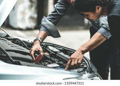 Man Help Woman Fix The Car Problem. He Pop Up The Car Hood To Repair The Damaged Part.