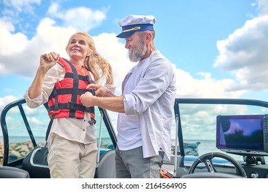 A Man In Helping A Blonde Woman To Put On The Life Vest