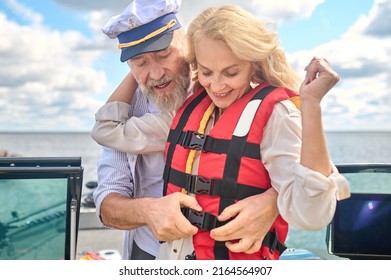 A Man In Helping A Blonde Woman To Put On The Life Vest