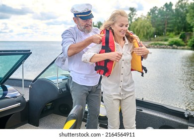 A Man In Helping A Blonde Woman To Put On The Life Vest