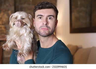 Man Helping Dog With A Muzzle After Medical Treatment