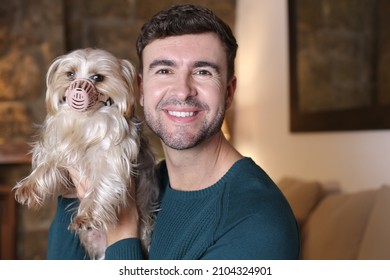 Man Helping Dog With A Muzzle After Medical Treatment