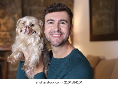 Man Helping Dog With A Muzzle After Medical Treatment