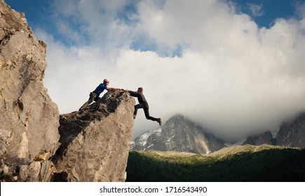 Man Helping Friend To Get Over The Cliff Edge