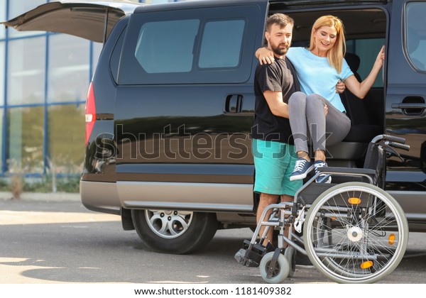 Man\
helping handicapped woman to sit in\
wheelchair