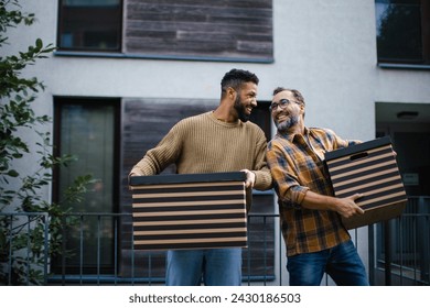 Man helping his friend move into new apartment in building. Man is moving into new flat, carrying box from the moving truck. - Powered by Shutterstock