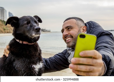 Man Helping His Grumpy Dog Firend To Take A Social Media Selfie Image Using A Smartphone