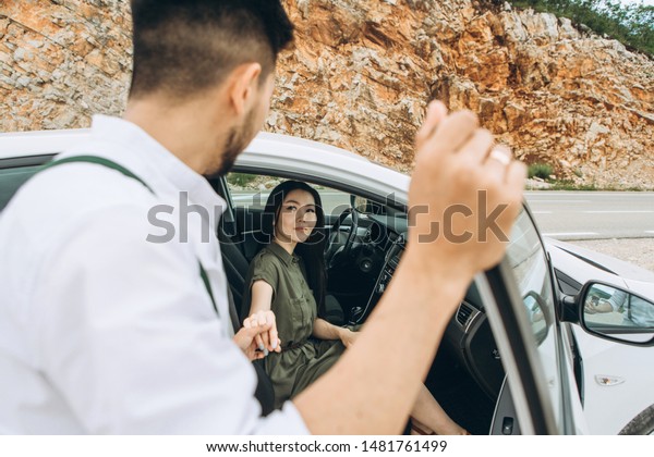 A man helps a woman get out of the car. He gave her\
his hand for this.