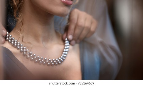 Man Helps Woman To Wear Jewelery. Friend Puts Necklace On Young Lady. Romantic Evening For Loving Couple On Black Background.