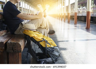 man with her backpack sitting in train station for start his travel program