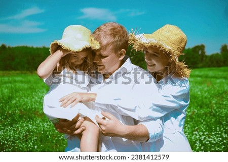 A man and her wife with their daughter are walking and playing on a summer meadow
