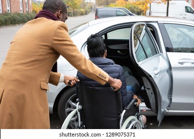 Man With Her Wife Woman Sitting On Wheelchair Moving Towards Car